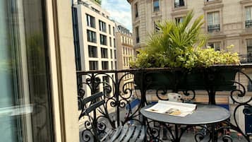 Un balcon avec une table, des chaises et un pot de fleurs.