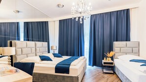 A modern hotel room with a large bed, a smaller bed, a desk, and a nightstand.