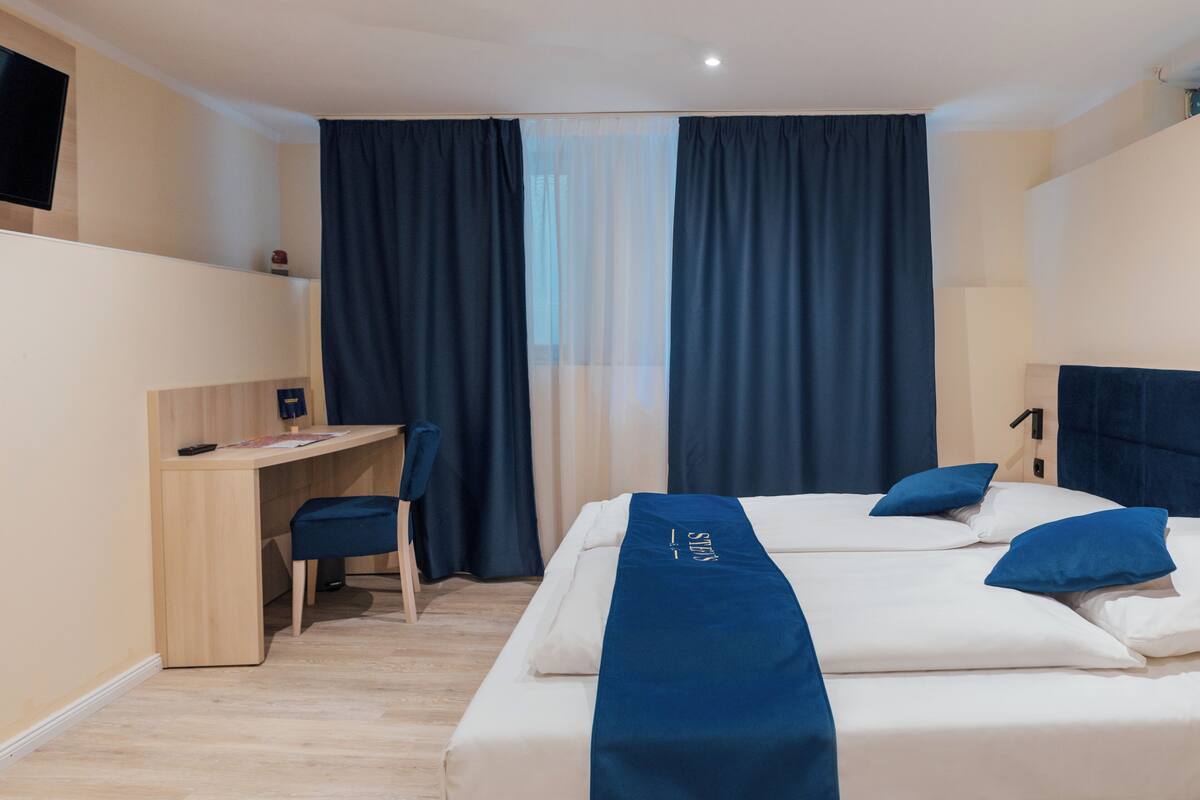 A hotel room with a bed, a desk, and a chair.