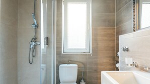 A modern bathroom with a glass-enclosed shower, a toilet, and a sink.