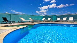 Ein Swimmingpool mit Liegestühlen und blauem Himmel.