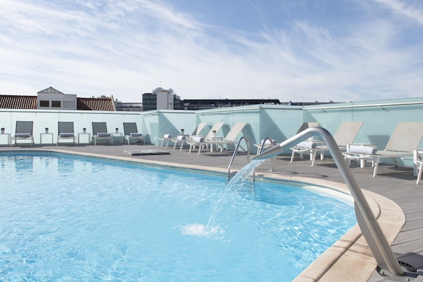 Una piscina al aire libre, sombrillas, tumbonas