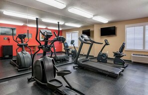 A gym with multiple exercise machines, a large mirror, and a television on the wall. - Extended Stay America Suites Orlando Southpark Commodity Cir (Orlando)