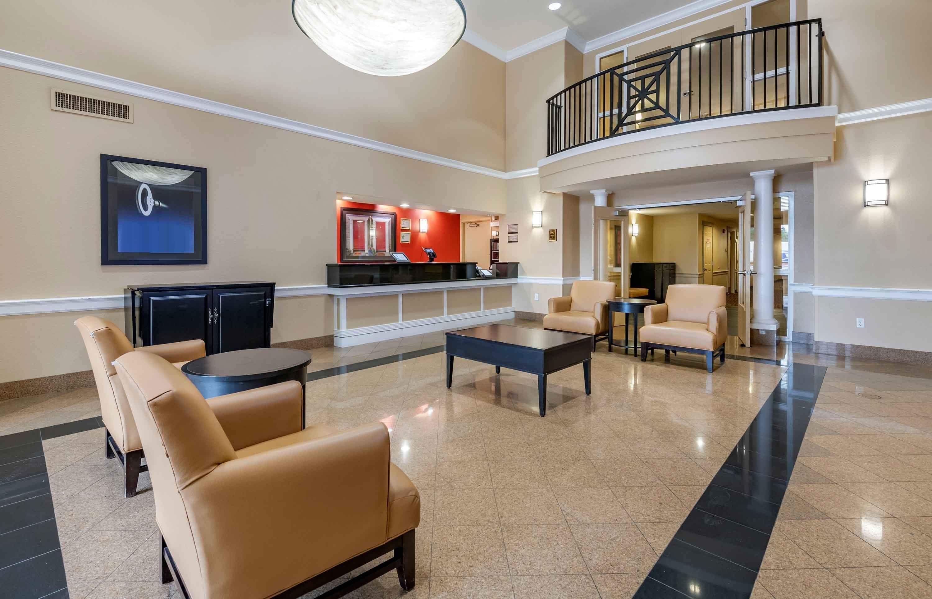 A lobby with a reception desk, seating area, and a staircase.