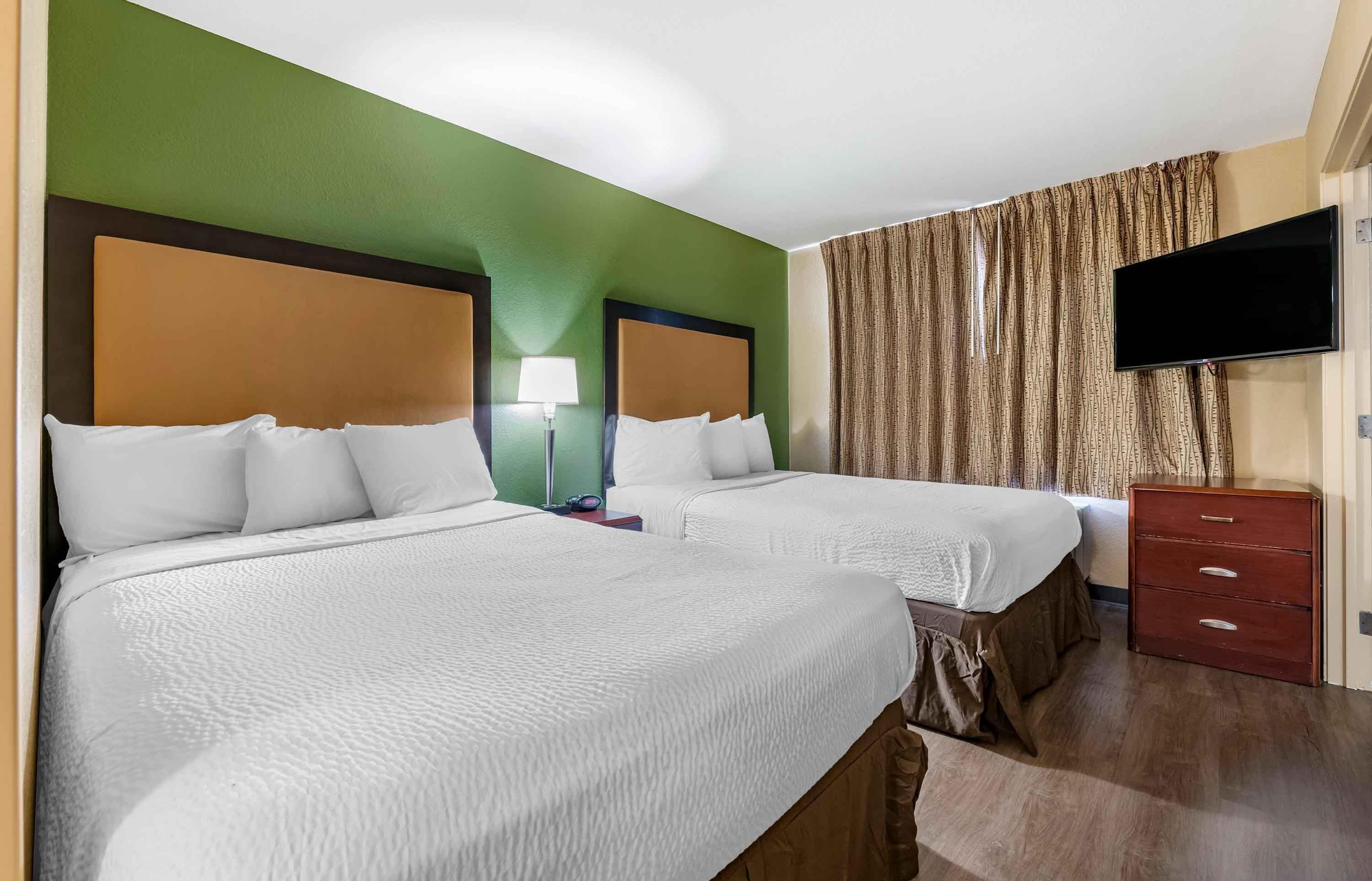 Una habitación de hotel con dos camas, un televisor, un tocador y una lámpara.