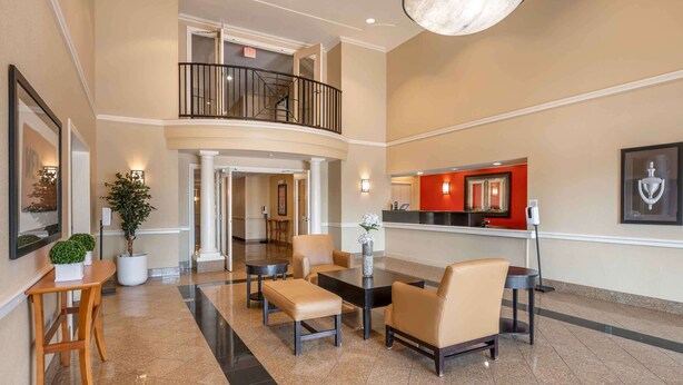 A hotel lobby with a reception desk, seating area, and a staircase leading to an upper level. - Extended Stay America Suites Indianapolis Northwest I465 (Indianapolis)