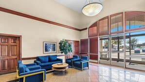 A lobby with a seating area, a plant, and a large window with blinds. - MainStay Suites Las Vegas Flamingo (Las Vegas)