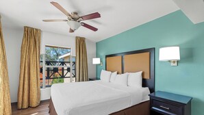 A hotel room with a bed, a nightstand, a ceiling fan, and a view through a window. - MainStay Suites Las Vegas Flamingo (Las Vegas)