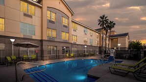 A hotel pool area with a swimming pool, lounge chairs, and a covered seating area. - MainStay Suites Las Vegas Flamingo (Las Vegas)