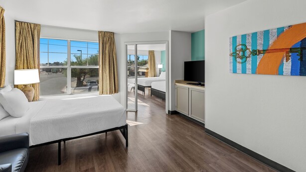 A hotel room with a bed, a TV, a desk, and a view of the outside. - MainStay Suites Las Vegas Flamingo (Las Vegas)