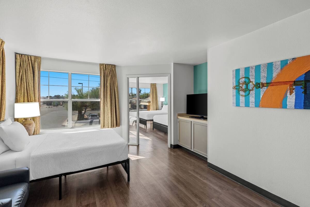 Une chambre d’hôtel avec un lit, une télévision, un bureau et une vue sur l’extérieur.