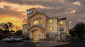 A MainStay Suites hotel with a lobby entrance, parking area, and a sunset sky. - MainStay Suites Las Vegas Flamingo (Las Vegas)