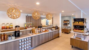 A modern breakfast bar with a coffee station, fruit display, and a variety of breakfast items.