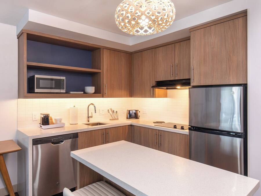 A modern kitchen with wooden cabinets, a stainless steel refrigerator, a microwave, and a dishwasher.