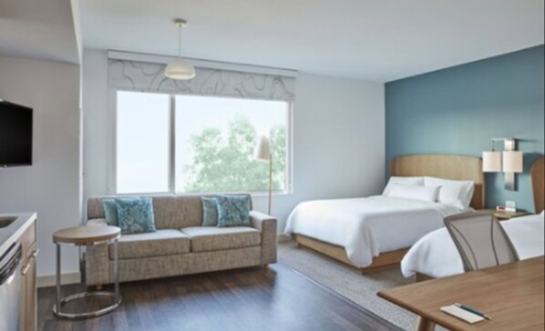 Una habitación de hotel con una cama, un sofá, una mesita y un televisor.