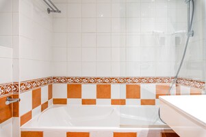 A bathroom with a bathtub, shower, and a white sink.