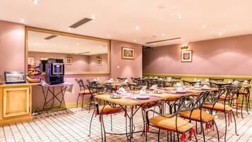 Uma área de refeições com várias mesas e cadeiras, um balcão de buffet e um espelho grande na parede.
