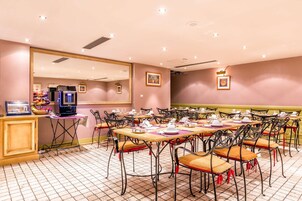 A dining area with multiple tables and chairs, a buffet station, and a large mirror on the wall.