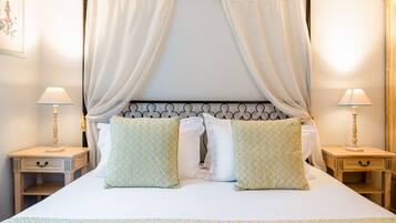 A bed with a canopy, two bedside tables with lamps, and patterned pillows.