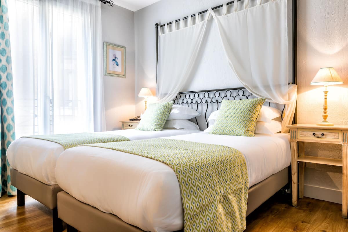 A double bed with a canopy, bedside tables with lamps, and a framed picture on the wall.