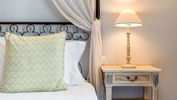 A neatly made bed with patterned bedding, a bedside table with a lamp, and a framed artwork on the wall.