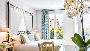 Un dormitorio con cama, dos lámparas de noche, una mesita de noche, una silla, una planta en maceta y vistas al exterior.