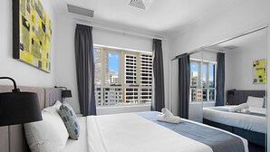 Habitación de hotel con una cama grande, una mesita de noche, un espejo y una ventana con cortinas.