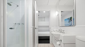 Un baño moderno con cabina de ducha de vidrio, ducha a ras de suelo, lavabo con espejo y un inodoro.