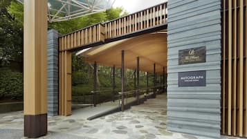 Un bâtiment moderne doté d’un sol en pierre, d’une passerelle en bois et d’une enseigne indiquant « The Prince Sakura Tower Tokyo ».