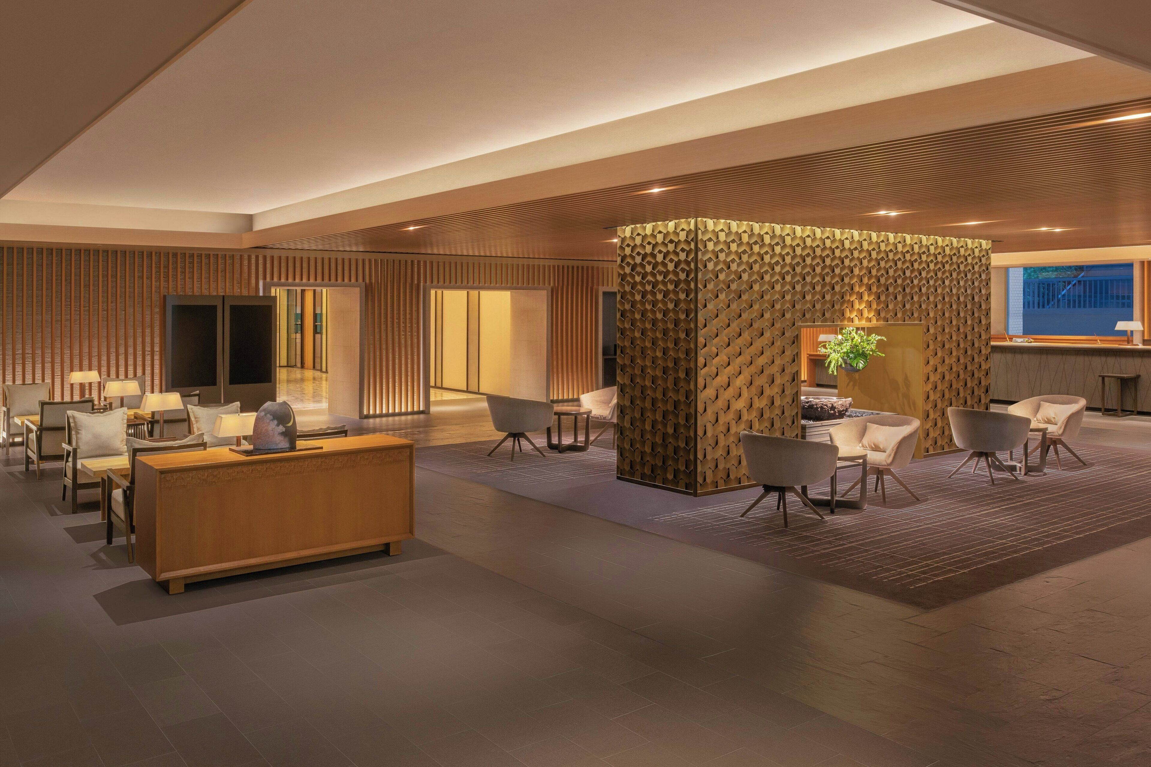 A modern lobby with a reception desk, seating area, and a decorative wall.