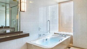 Ein modernes Badezimmer mit einer großzügigen Badewanne, einer Duschkabine aus Glas und einem Waschtisch mit Spiegel.
