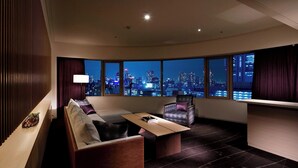 A modern hotel room with a large panoramic window, a sofa, a chair, a small table, and a lamp. - The Prince Sakura Tower Tokyo, Autograph Collection (Tokyo)