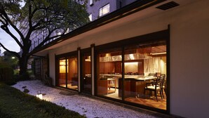 A modern house with a glass-enclosed dining area and kitchen, surrounded by a gravel path and greenery. - The Prince Sakura Tower Tokyo, Autograph Collection (Tokyo)
