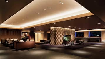 Una hall moderna con reception, area relax e parete decorativa.