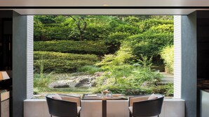 A modern dining area with a view of a lush garden through a large window. - The Prince Sakura Tower Tokyo, Autograph Collection (Tokyo)