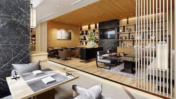 A modern hotel lobby with a wooden reception desk, seating area, and a TV mounted on the wall.