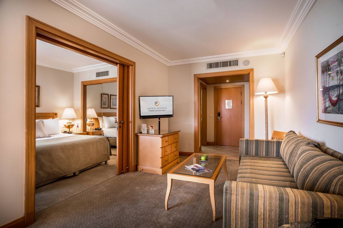 A hotel room with a bed, a sofa, a coffee table, a TV, and a desk.