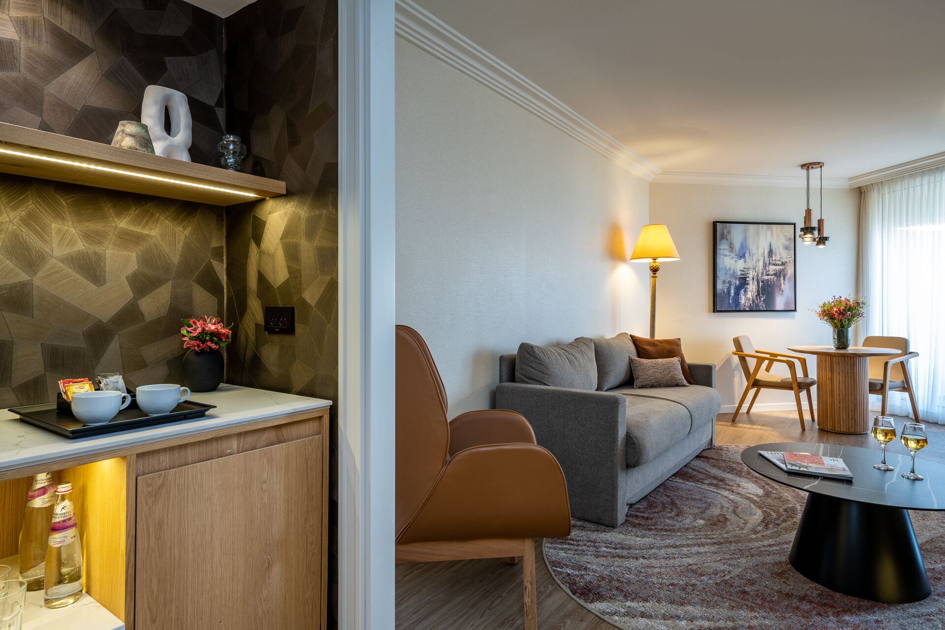 Una sala de estar moderna con un sofá gris, una mesa de centro de madera y un comedor con una mesa redonda y sillas.