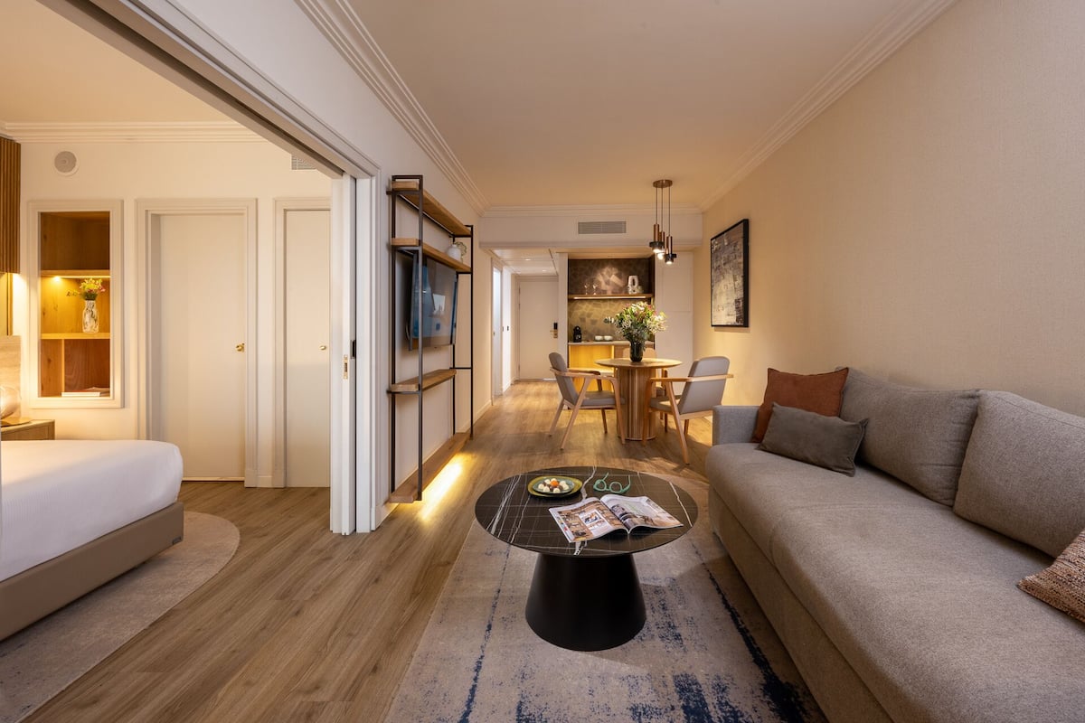 A modern living room with a sofa, a coffee table, and a dining area with chairs and a small table.