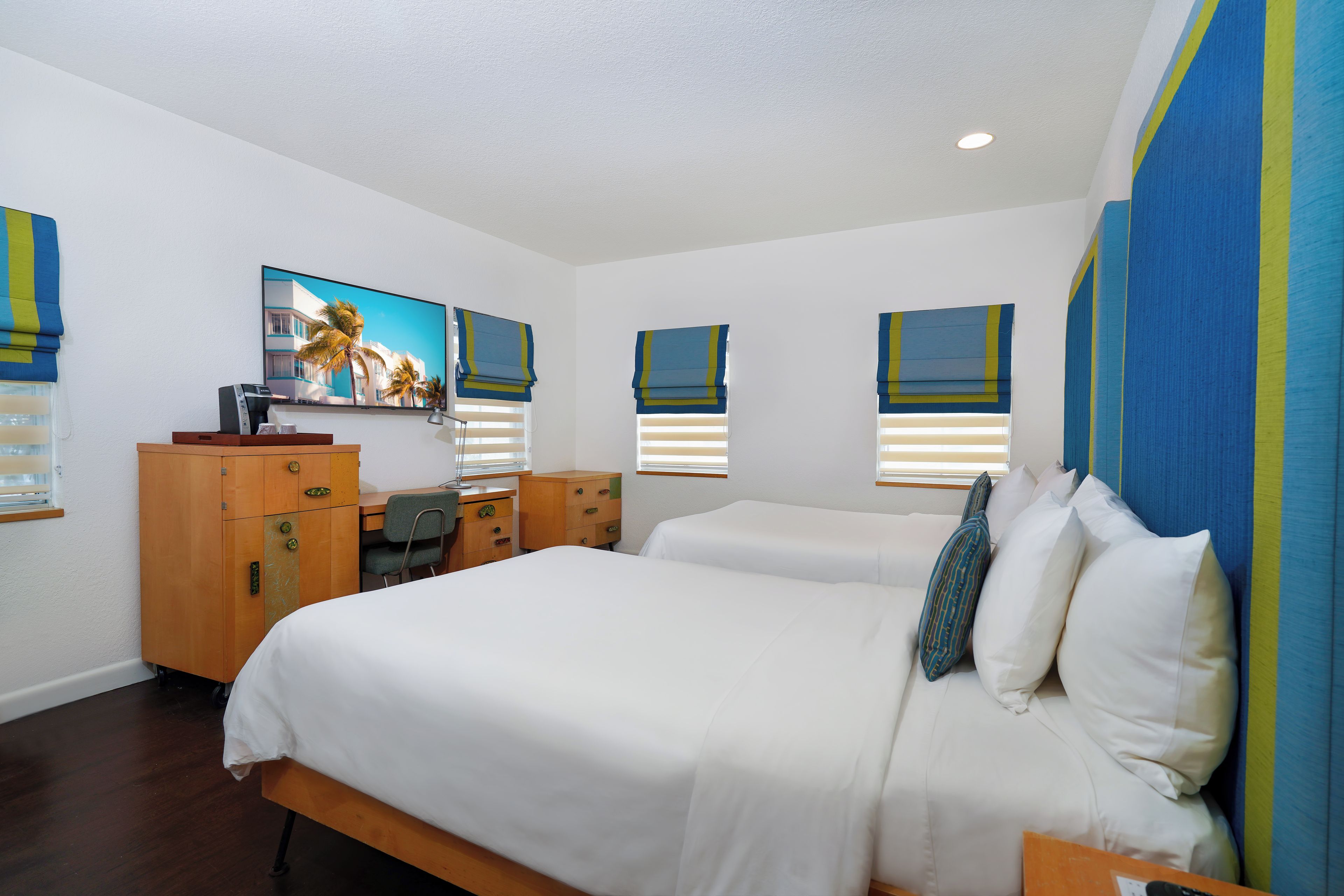 A hotel room with a bed, a desk, a chair, and a television.
