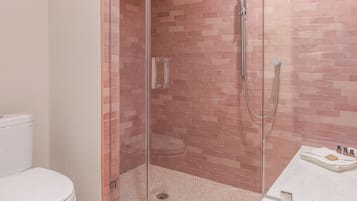 A bathroom with a glass-enclosed shower, a toilet, and a sink with a mirror.