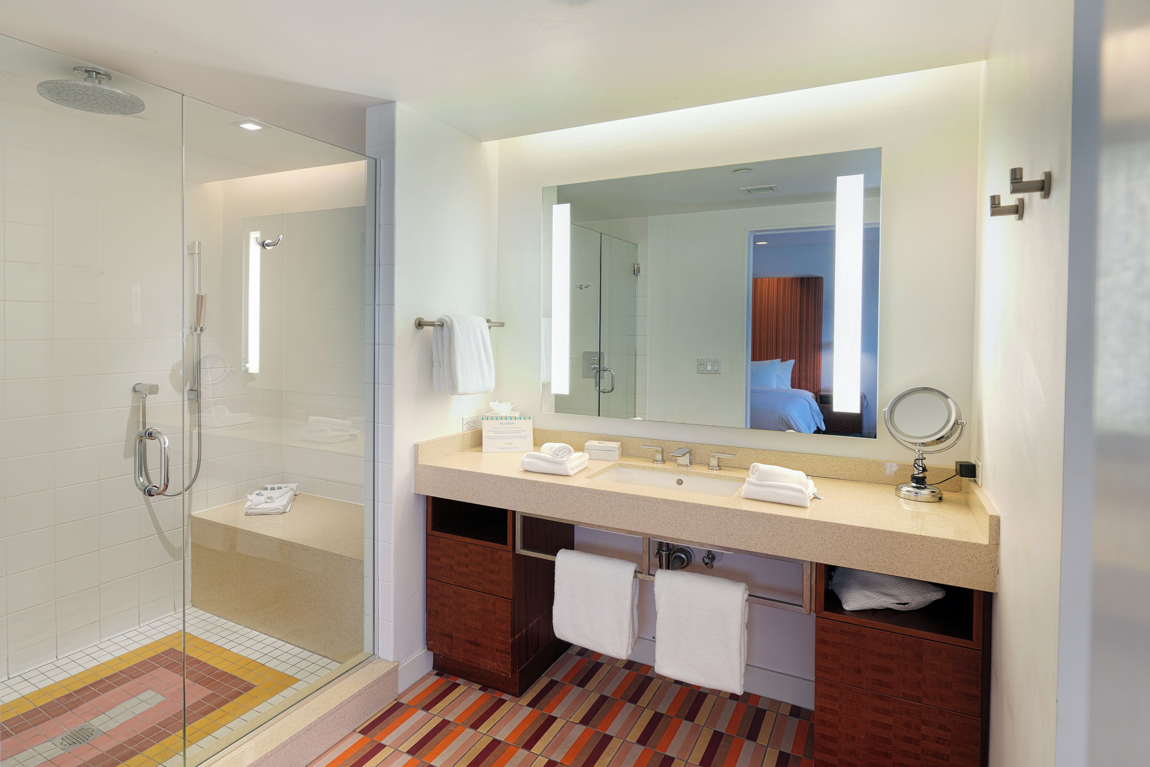 A modern bathroom with a glass shower enclosure, a vanity with a mirror, and a towel rack.