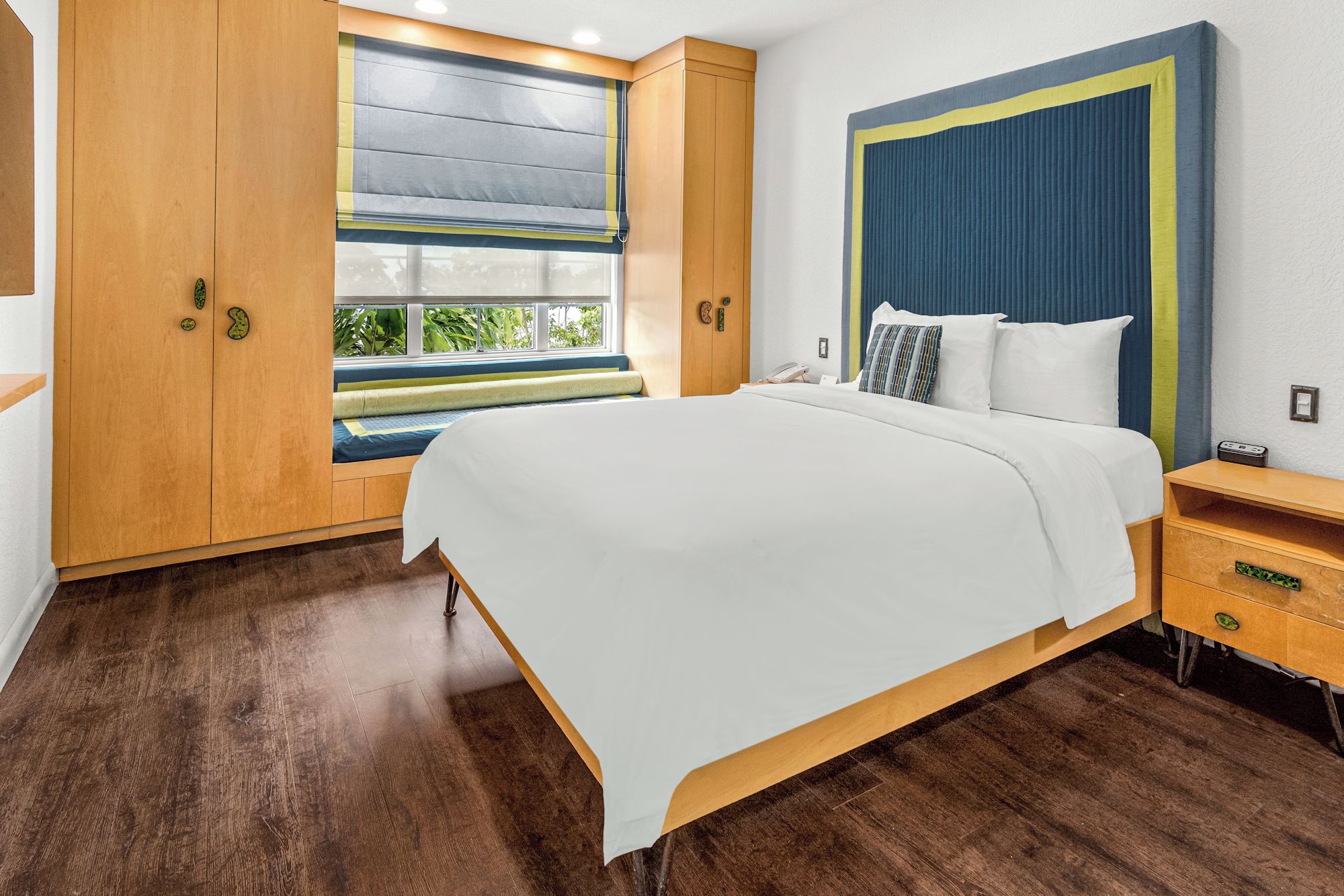 Un dormitorio moderno con una cama grande, un armario de madera y una ventana con persianas.