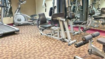 A gym with various exercise equipment, including treadmills, weight machines, and free weights.