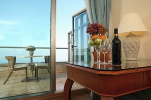 A balcony with a table, chairs, a vase with flowers, a fruit bowl, wine glasses, a bottle of wine, and a lamp. - Crowne Plaza Haifa by IHG (Haifa)
