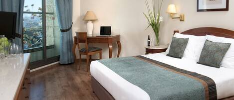 A hotel room with a bed, desk, chair, and a window with curtains.
