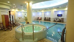 A large indoor swimming pool with a hot tub, lounge chairs, and a television screen. - Crowne Plaza Haifa by IHG (Haifa)