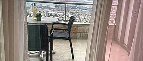 A balcony with a table and chairs, overlooking a cityscape.