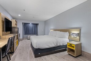 A modern hotel room with a bed, desk, and TV. - Days Inn by Wyndham San Antonio Downtown (San Antonio)