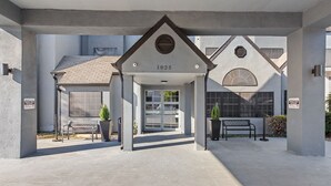 A building entrance with a covered area, a number sign, and a bench.